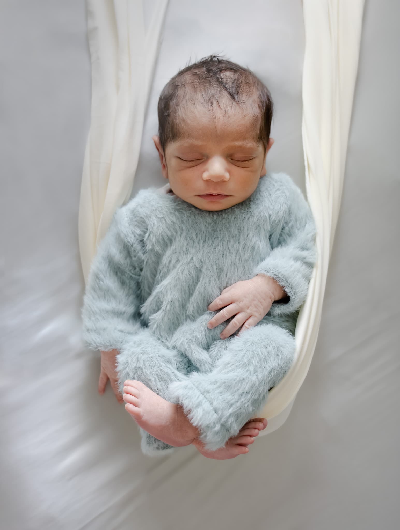 Sleeping newborn wrapped in soft blue fabric